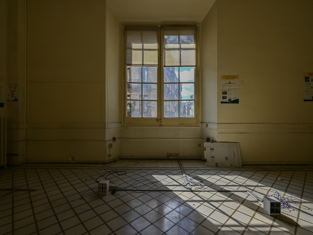 Habitación vacía con luz natural, paredes amarillas y ventanas grandes. Suelo de azulejos.