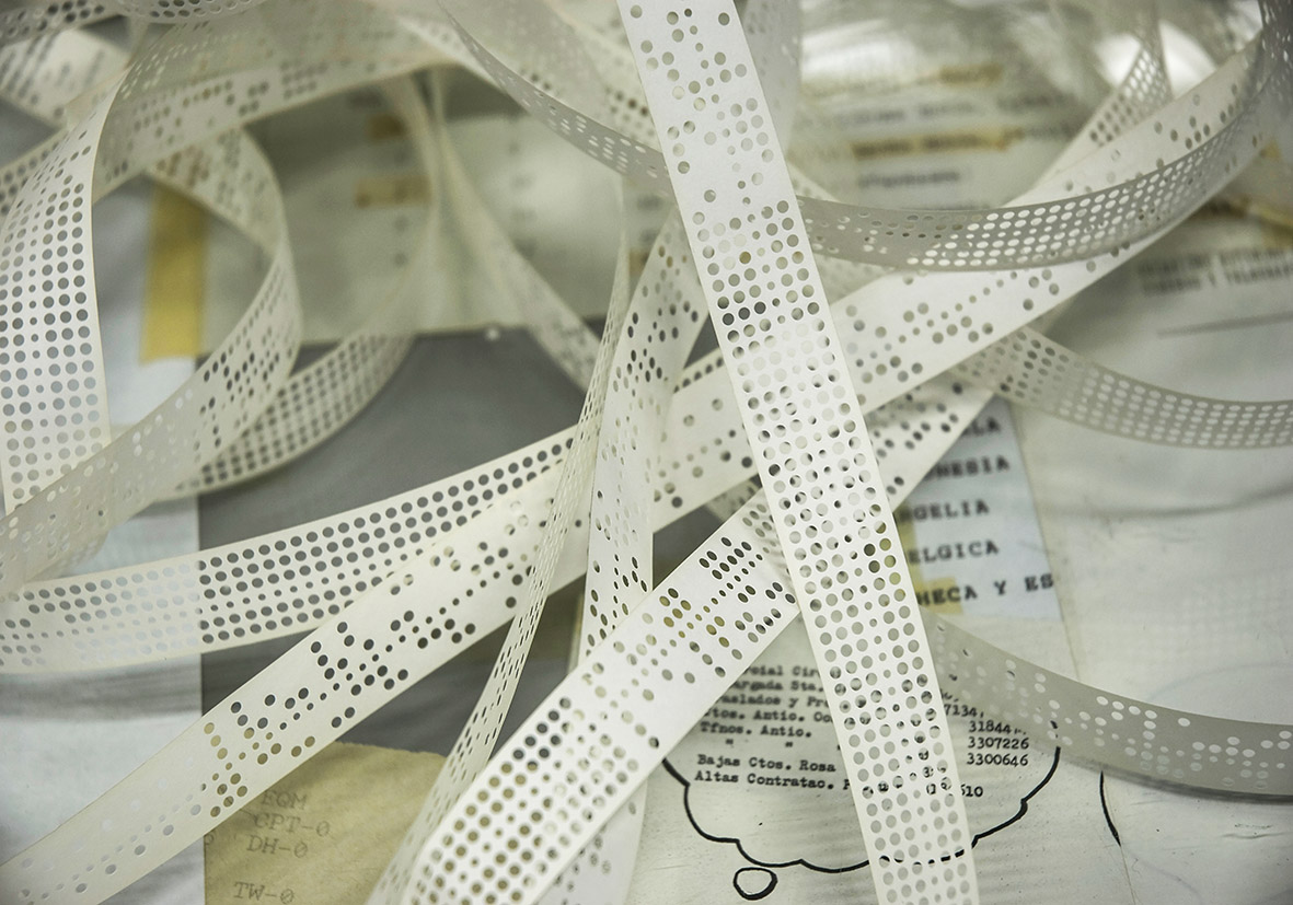 Tiras de papel perforadas con datos impresos en un desorden sobre una superficie.