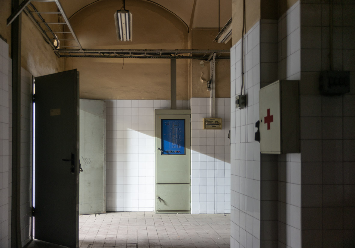 Pasillo de un edificio abandonado con puertas y luz natural que entra por una ventana.