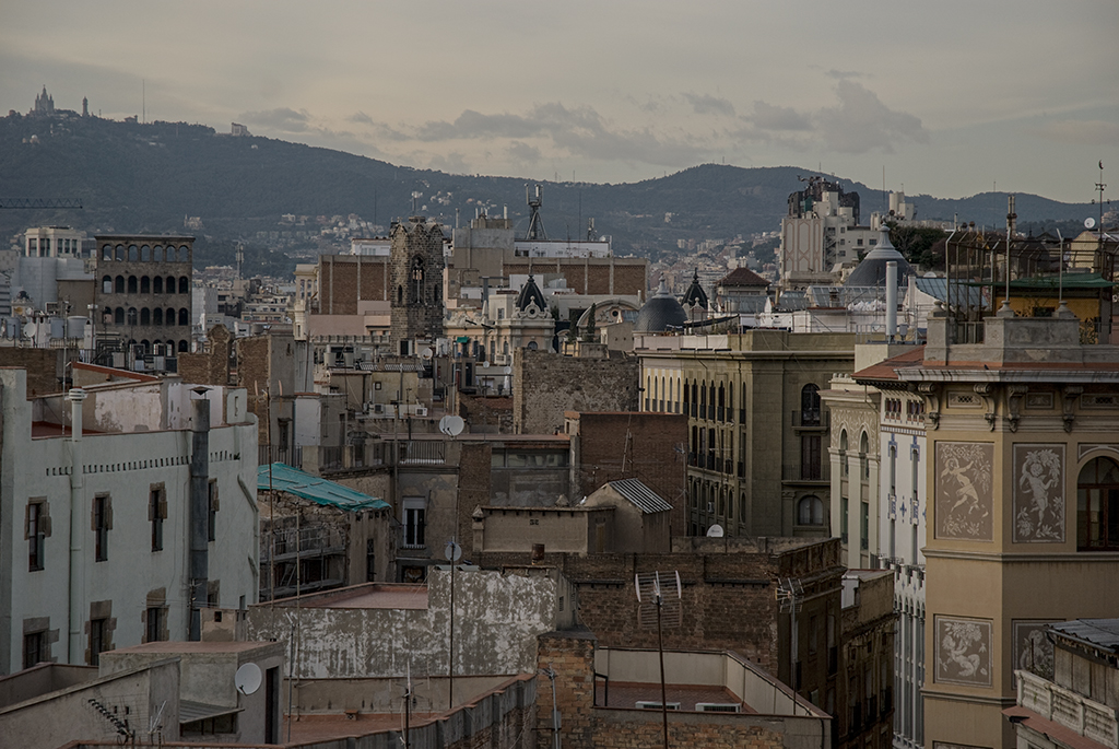 Vista panorámica de edificios y colinas en una ciudad, con cielo nublado.